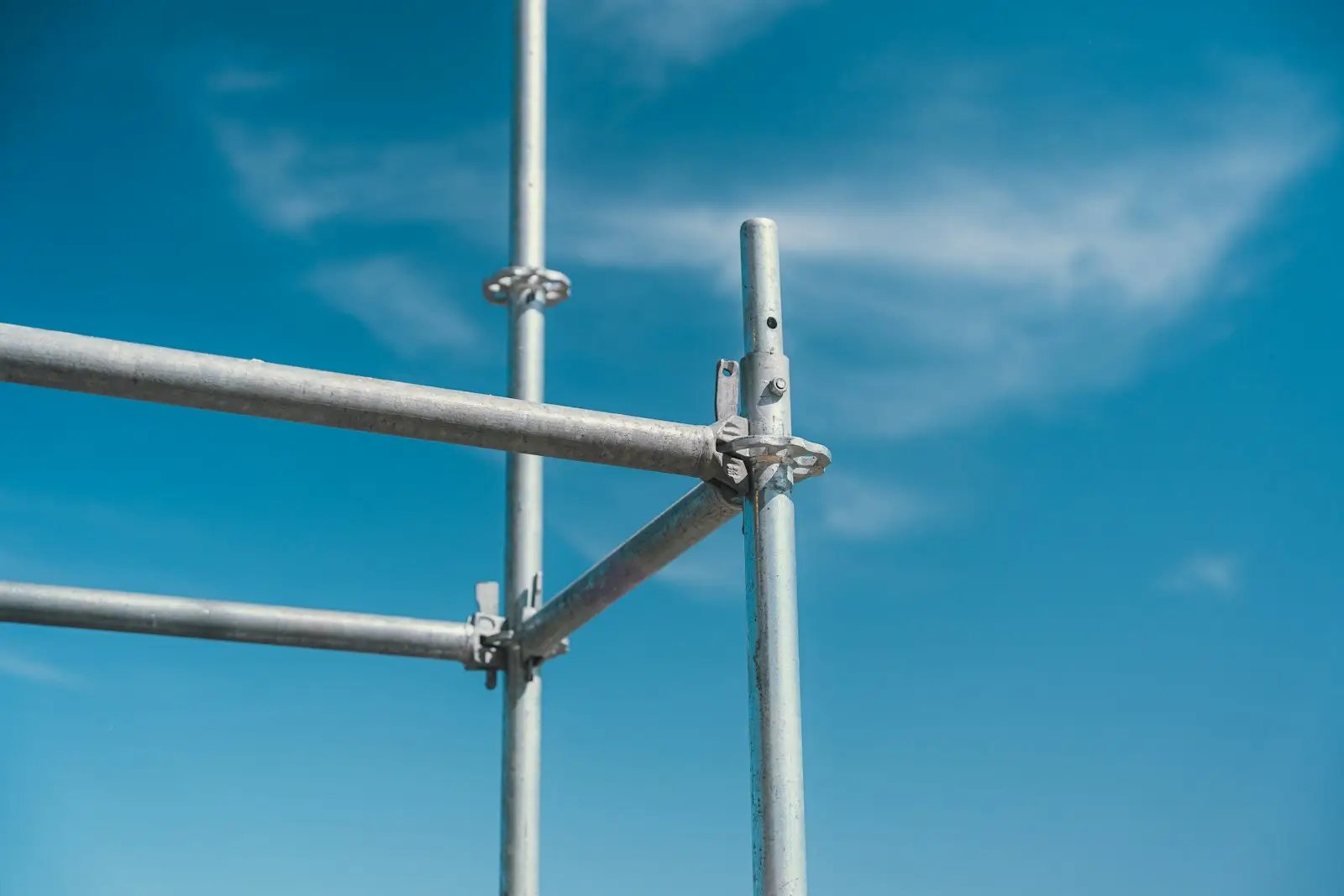 A scaffold coupler joining two tubes, against the sky