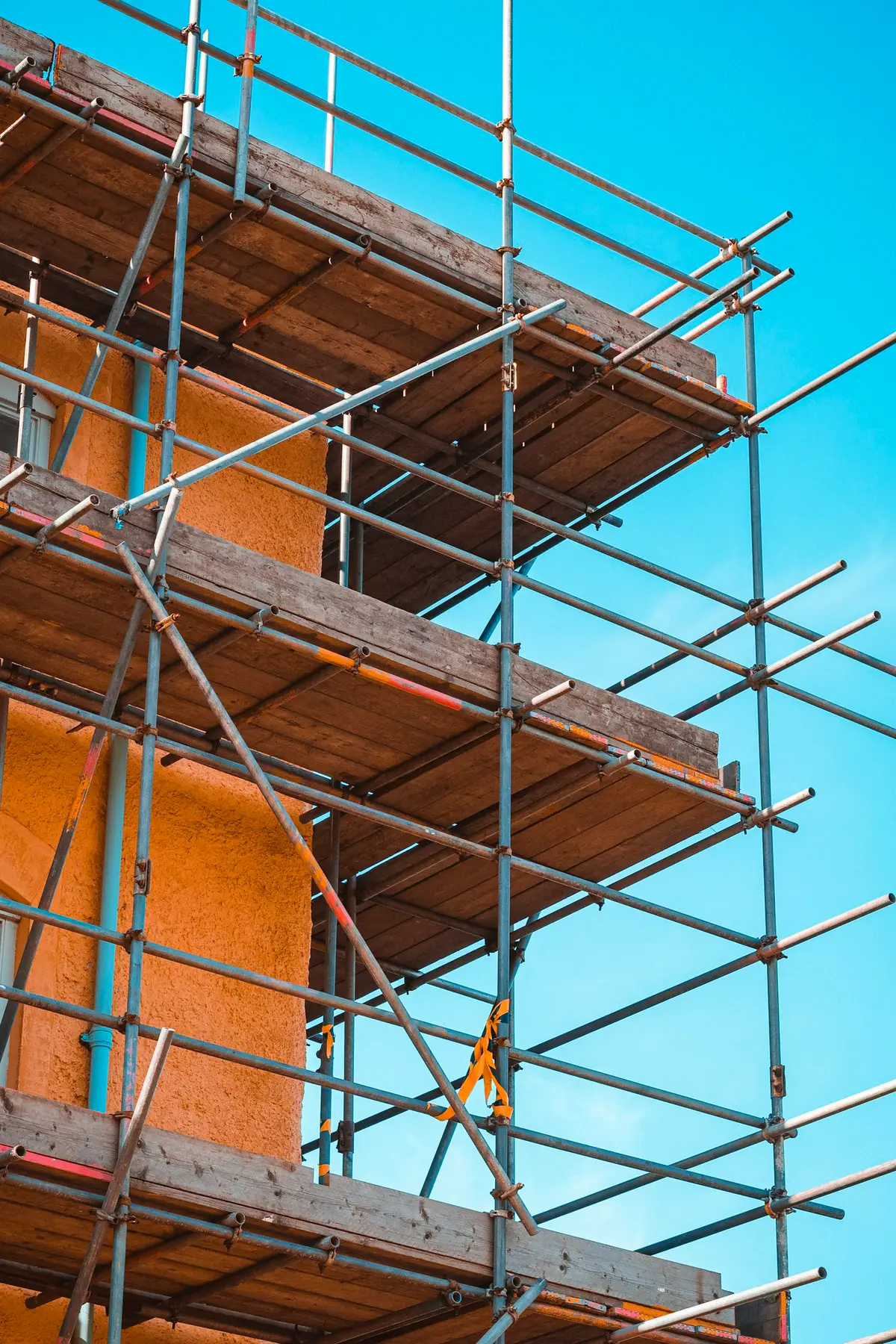 Tube and fitting scaffolding with boards and guardrails against a blue sky