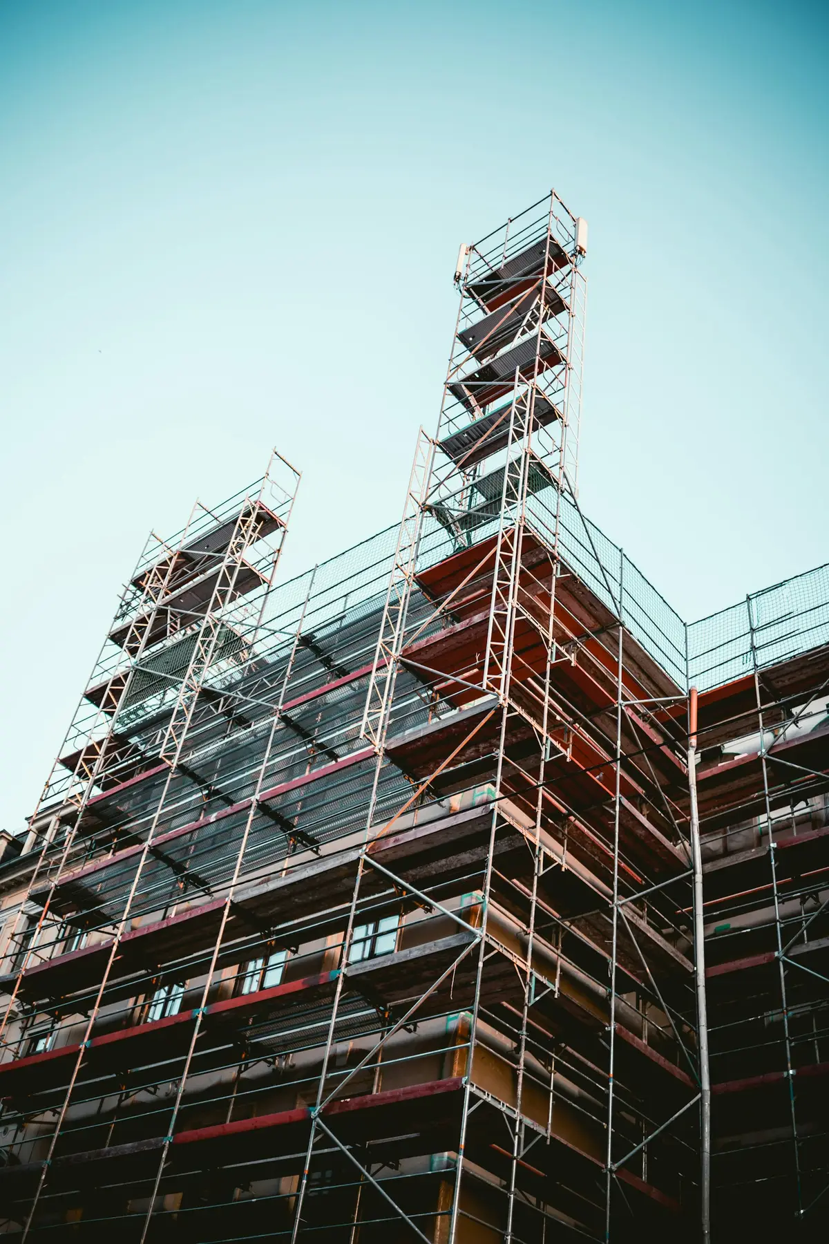 A tall building wrapped in scaffolding, seen from below